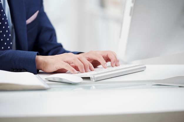 Free photo cropped anonymous officer typing on white keyboard