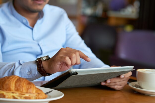 Cropped business executive using wireless device in a cafe
