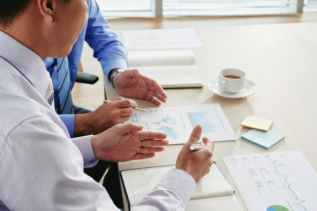 Cropped businessmen discussing analytical visuals and working on business strategy