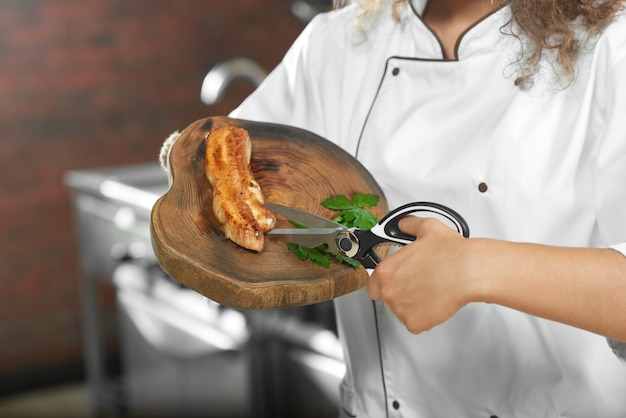 Free photo cropped close up of a female chef using scissors while working at her kitchen cutting grilled chicken preparing delicious dish.