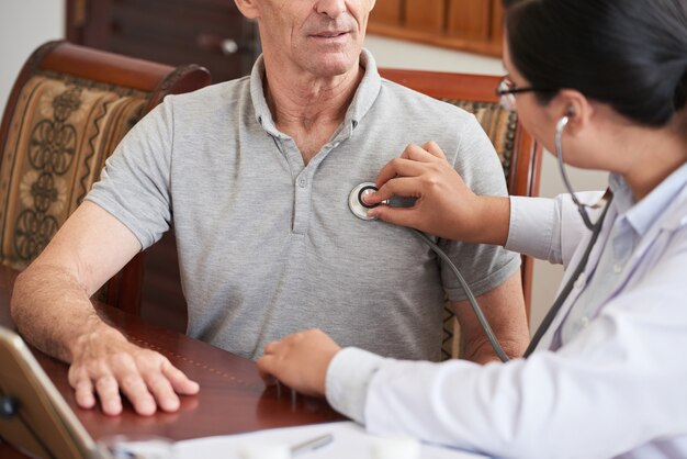 Cropped doctor checking up the heartbeat of senior patient