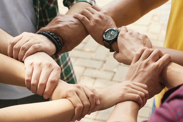 Cropped friends holding wrists of each othe in chain to support and collaborate