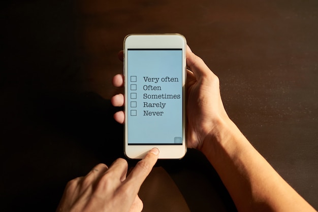 Mani ritagliate compilando il sondaggio online sul touchscreen dello smartphone