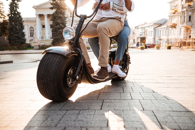 Cropped image of african couple rides on modern motorbike on the street