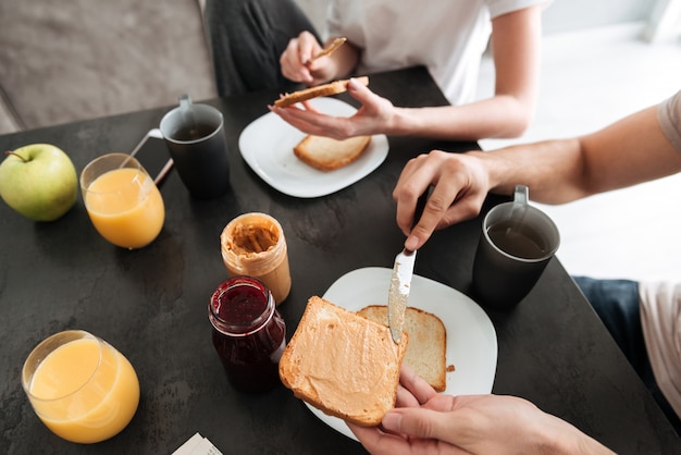 カップルのトリミングされた画像は、キッチンでおいしい朝食を持っています