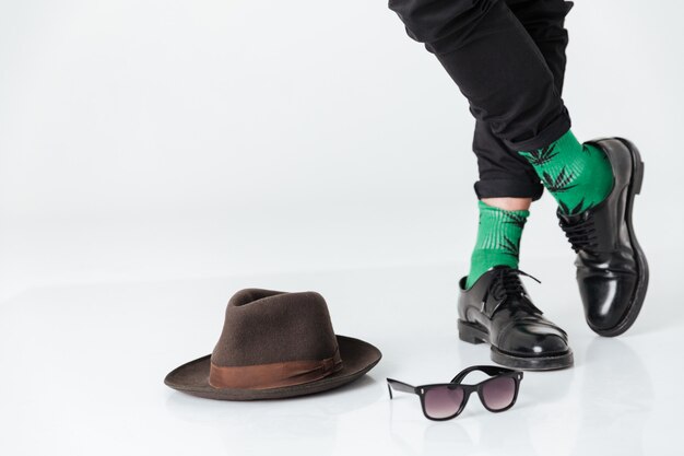 Cropped image  man standing on floor near hat and sunglasses