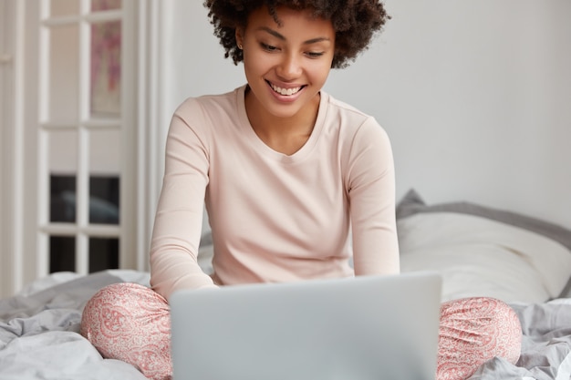 Обрезанное изображение темнокожей девушки сидит перед портативным компьютером
