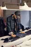 Free photo cropped image of tailor makes measurements of jeans with a meter at sewing workshop.