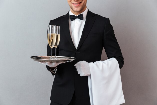 Cropped image of waiter holding glasses of champagne and towel.