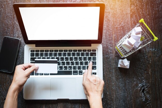 Cropped image of woman inputting credit card information and key on phone or laptop while shopping online concept