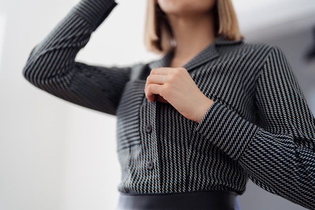 Cropped image of a woman with beautiful dark shirt with lines in a blurred light interior