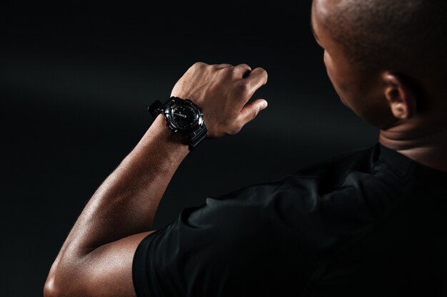 Cropped image of young afro american man, looking at watch