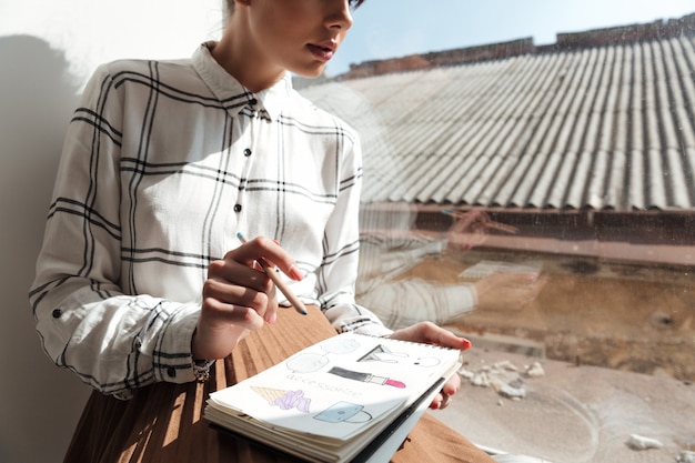 Free photo cropped image of a young woman artist drawing sketches