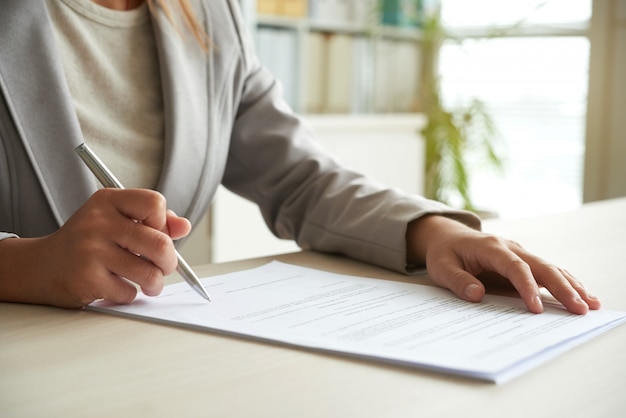 Cropped mid-section of unrecognizable woman signing the document