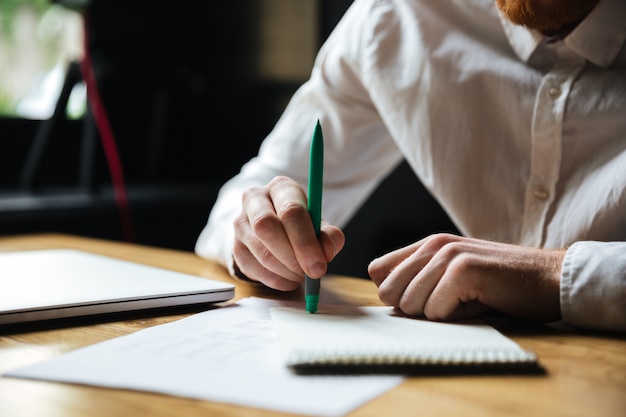 Free photo cropped photo of man in white shirt holding green pen