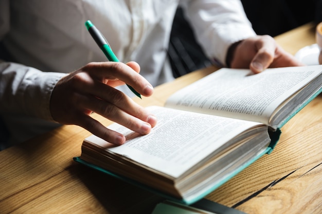 Cropped photo of man in white shirt reading book