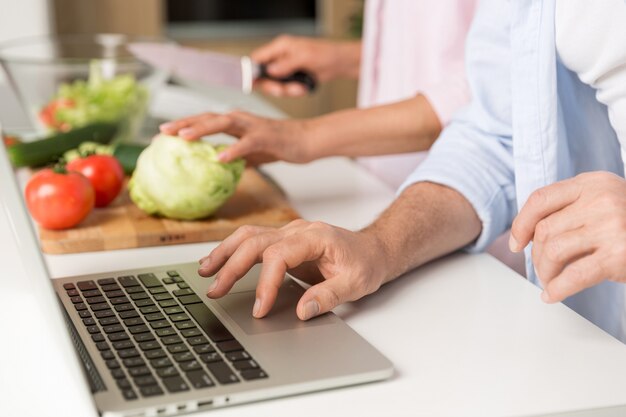 Cropped photo of mature loving couple family using laptop cooking