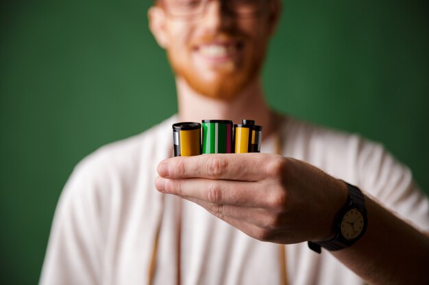 Cropped photo of readhead bearded photographer, holding camera rolls,