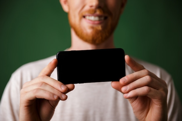 Free photo cropped photo  redhead bearded man in white tshirt makes a photo on smartphone mobile