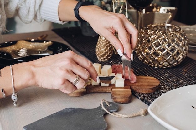 Cropped photo of woman tasting cheese on a wooden board with Christmas decorations in the background