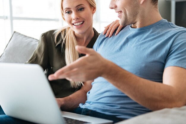 Cropped photo of young lovers using laptop computer on sofa