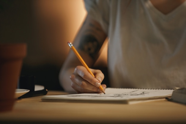 Cropped photo of young woman designer writing notes.