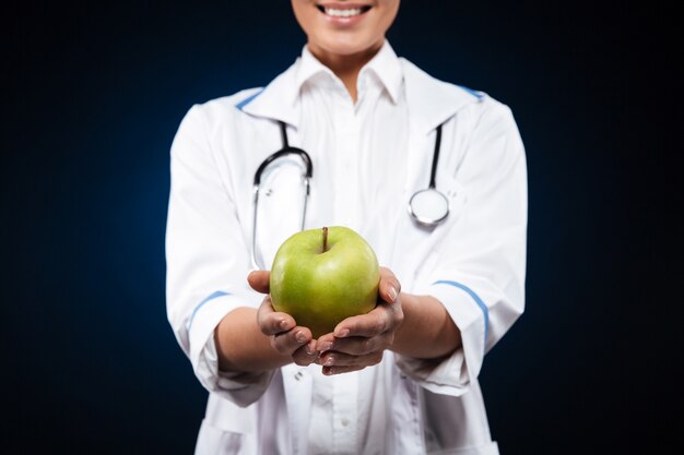 녹색 사과 들고 의료 가운에 젊은 여자의 자른 사진