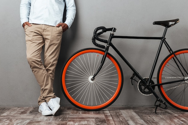 Cropped picture of african man standing near bicycle