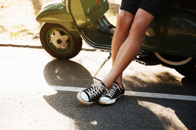 Cropped picture of young man standing near scooter outdoors.