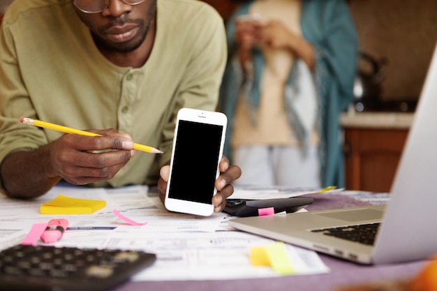 Cropped portrait of African-American male sitting at kitchen table with open laptop