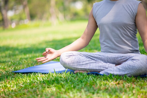 Cropped portrait of man sitting on grass in lotus pose. 