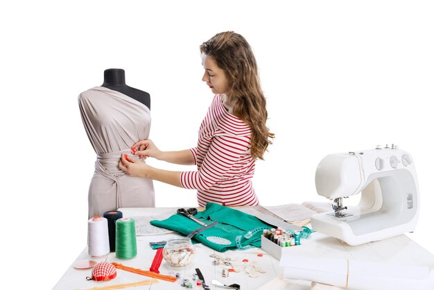 Cropped portrait of young woman sewing dress isolated over white background