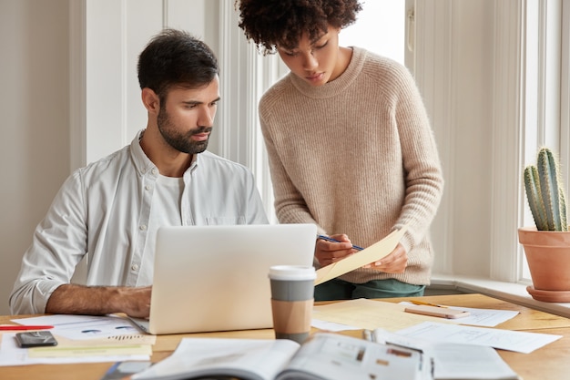 Cropped shot of pretty black woman dictates information to her assistant, work as team at cozy room