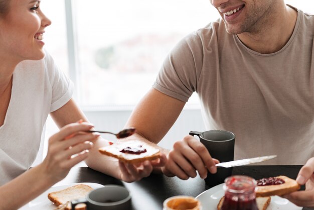 Обрезанный снимок улыбающиеся пары едят завтрак по утрам