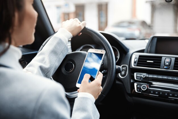 Cropped shot of woman hands holding wheel and smartphone.