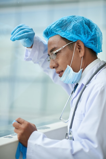 Free photo cropped side view of surgeon tired after the surgery leaning at the window