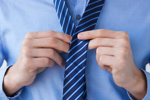 Cropped View of Business Man Tying Necktie