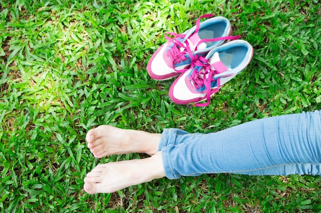 Free photo cropped view of girl legs and sneakers on grass