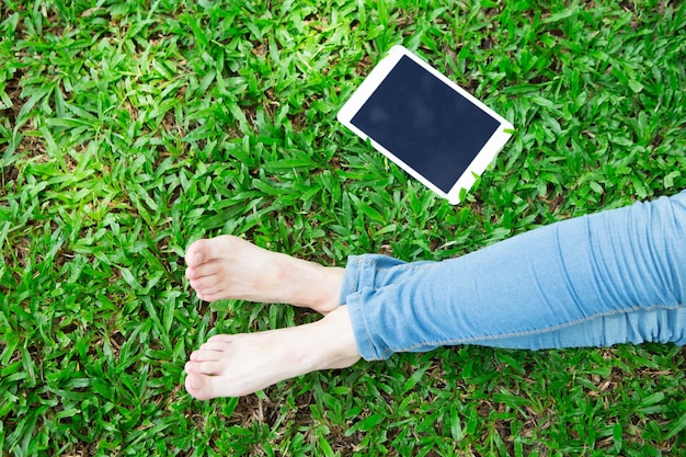 Free photo cropped view of girl and tablet on grass