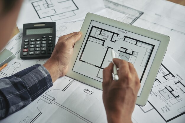 Cropped view of male hands holding the digital pad examining blueprint