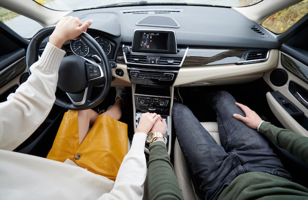 Обрезанный вид романтической пары в машине, держащейся за руки