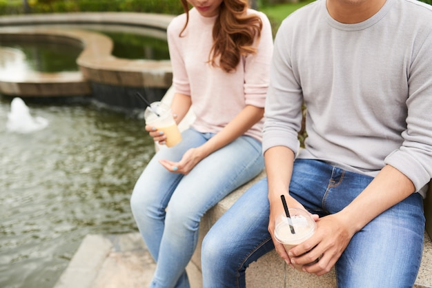 Free photo cropped view of unrecognizable couple enjoying cocktails in the park