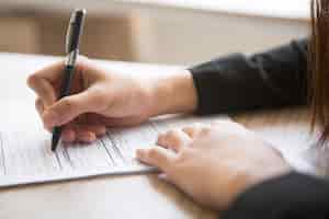 Free photo cropped view of woman filling in application form