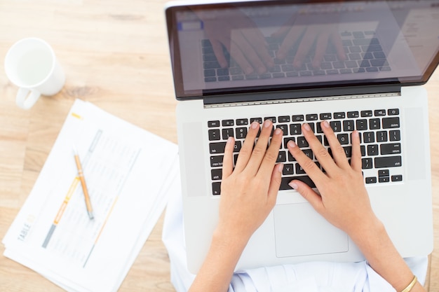 Foto gratuita vista ritagliata delle mani di donna che digitano sul computer portatile