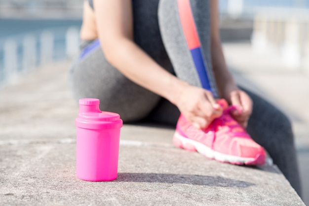 Free photo cropped view of woman tying shoelace outdoors