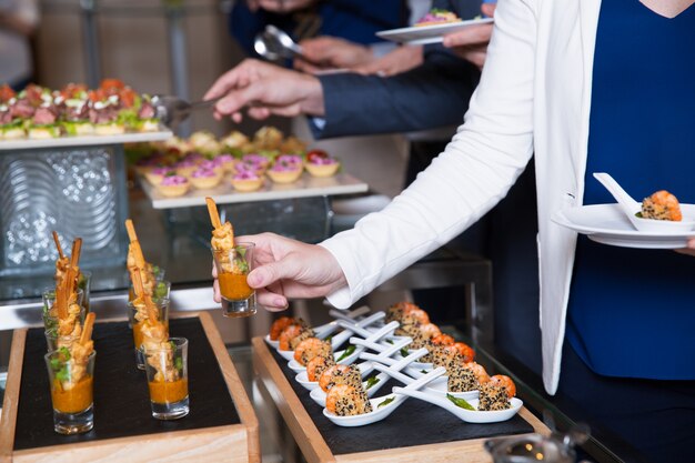 Cropped Woman Taking Snack from Buffet Table