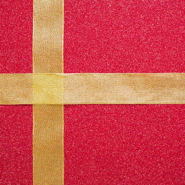 Cross from ribbons on red background