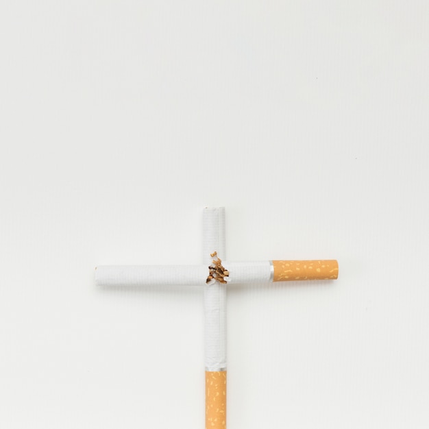 Бесплатное фото Крест знак из сломанной сигареты на белом фоне