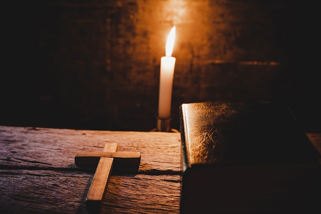 Croce con la bibbia e la candela su un vecchio tavolo di legno di quercia.