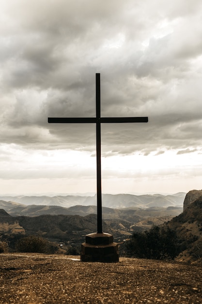 Cross with an overlooking view of mountains under a cloudy gray sky